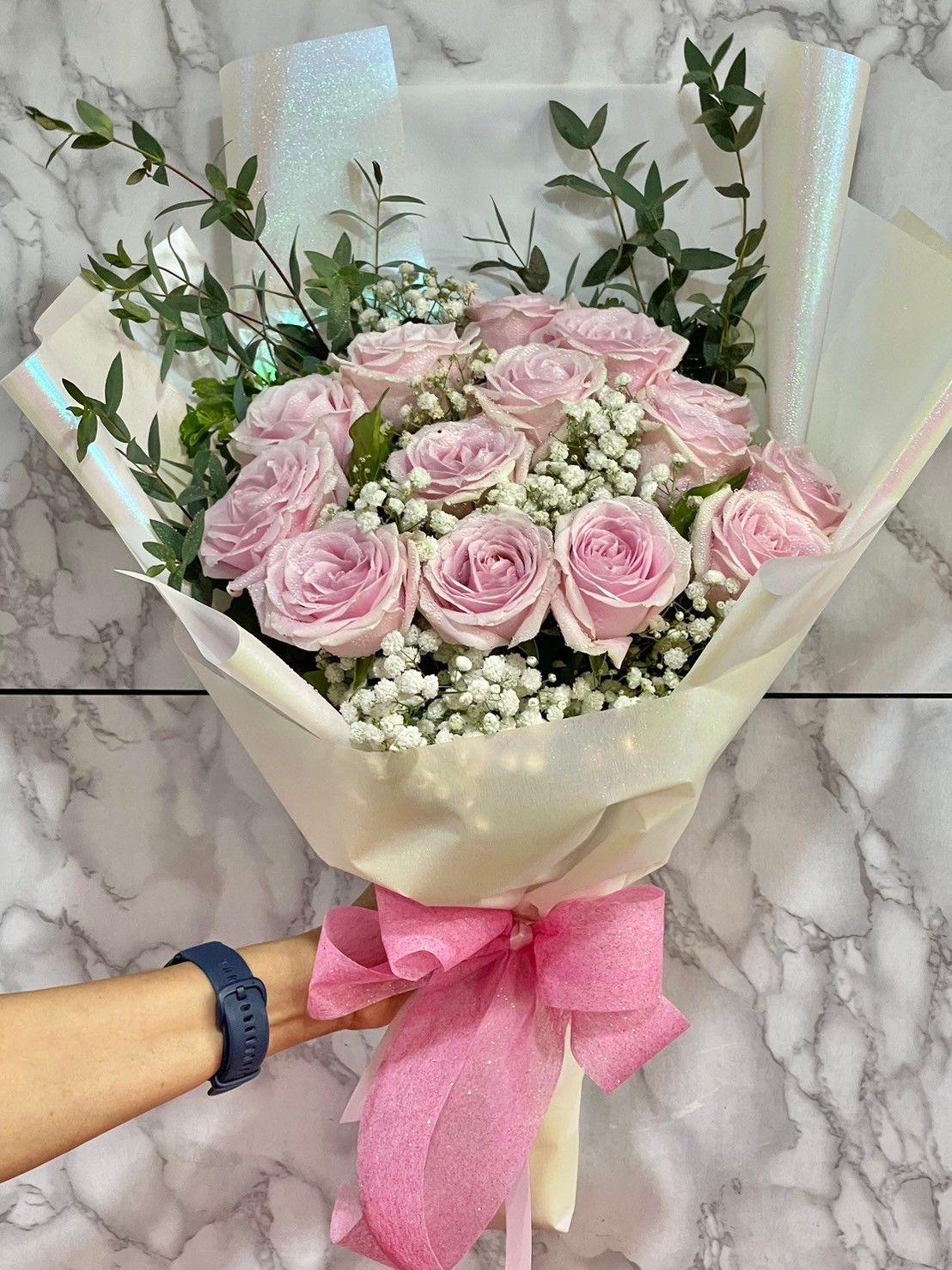 ช่อกุหลาบสีชมพูอ่อนห่อด้วยกระดาษสีขาวมุก